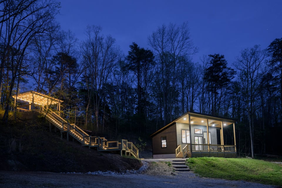 Full property at night, cabin and hot tub deck illuminated on the mountaintop