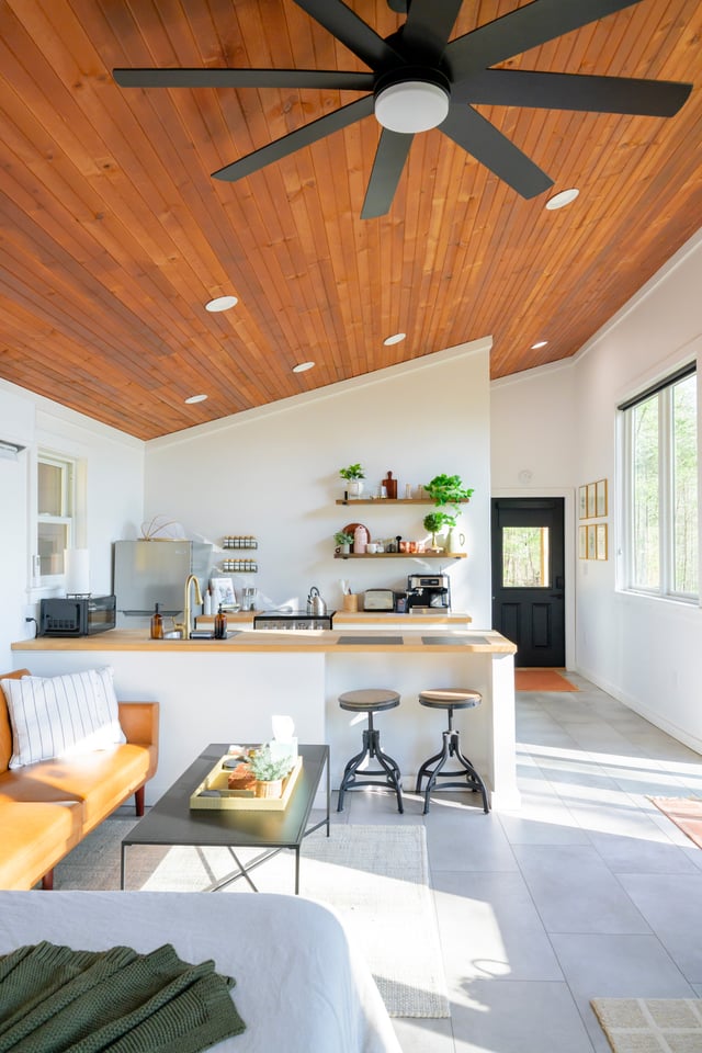 Open-plan living and kitchen area with cedar ceiling, leather sofa and large windows