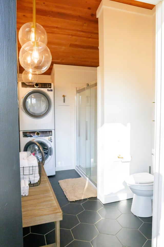 Spa bathroom with dark hexagonal tile, round mirror and globe pendant lights