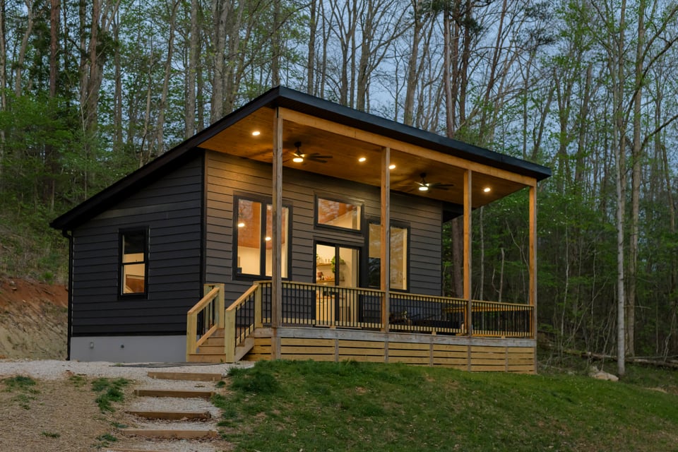 Cabin exterior at night, warm interior lights glowing against the dark forest
