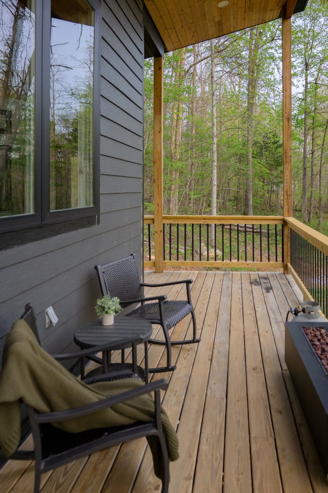 Covered porch with rocking chairs, fire table and forest view