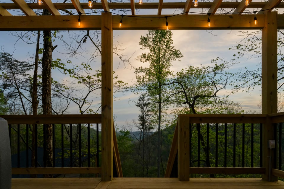 Lit staircase leading up through the forest to the hot tub pergola at dusk