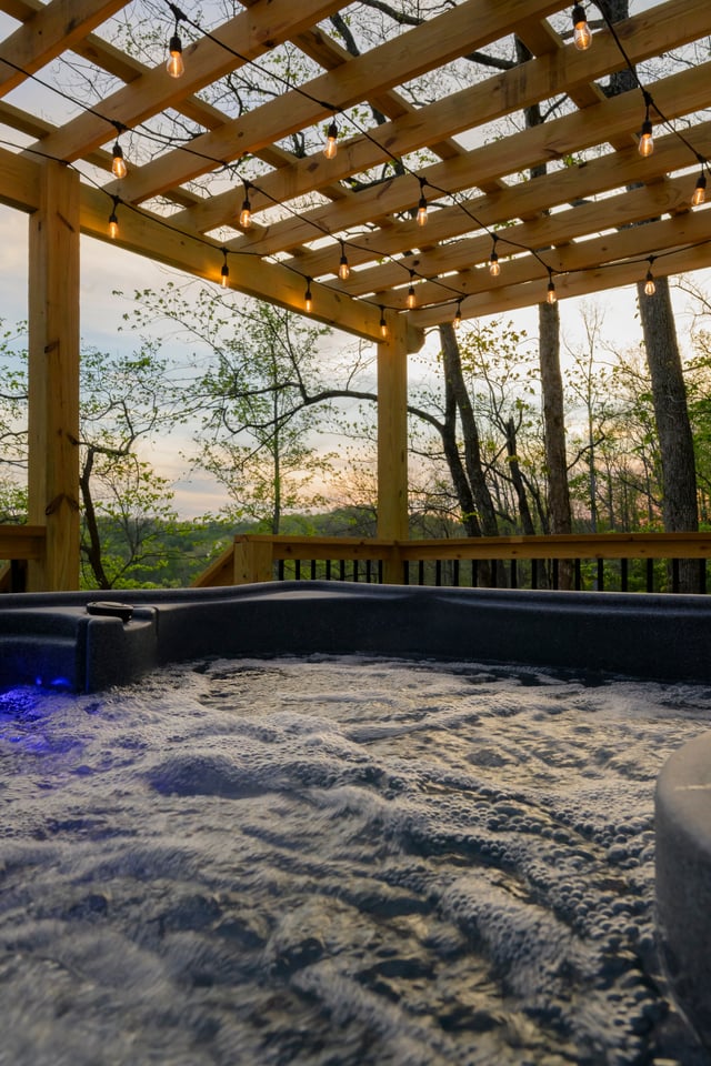 Hot tub at golden sunset, steam rising, ridgeline view beyond